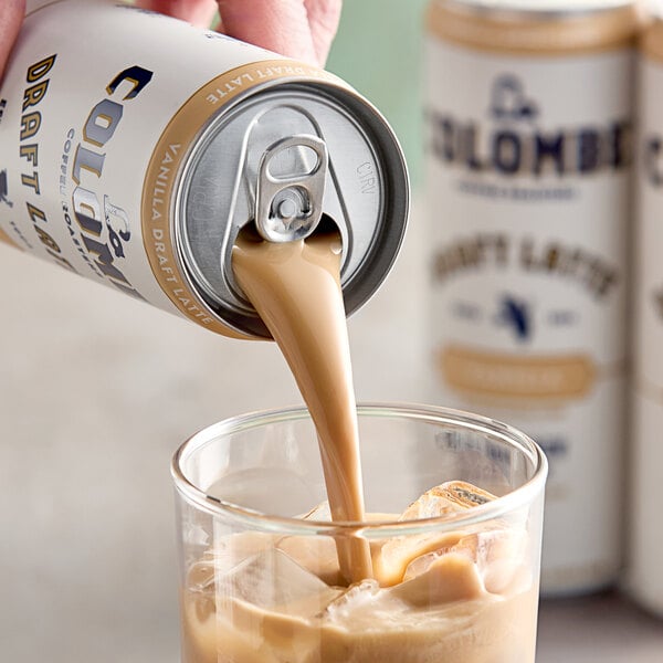 A person pouring La Colombe Vanilla Draft Latte from a can into a glass.