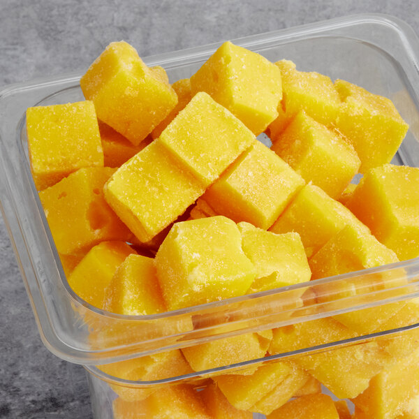 A plastic container filled with yellow mango cubes.