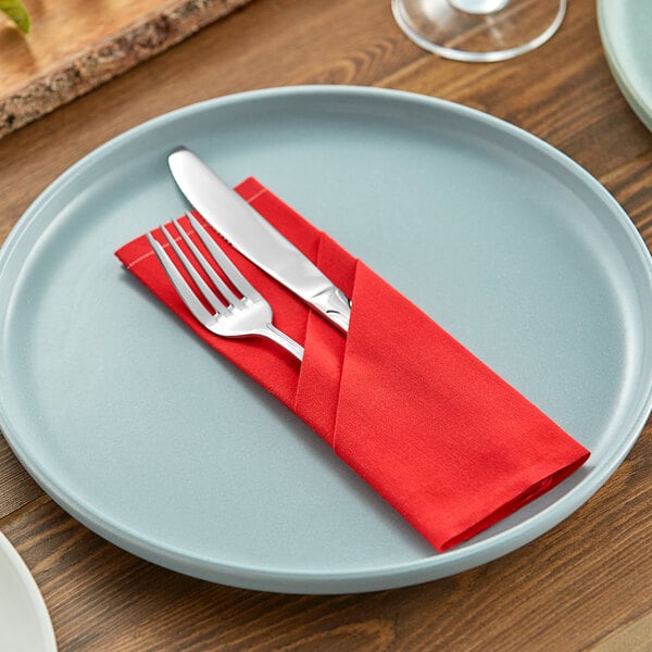 A fork and knife on a red napkin.