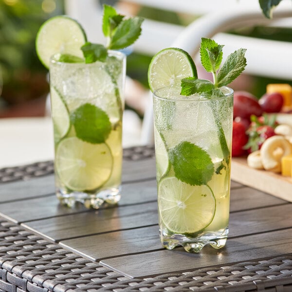 Two Acopa Endure highball glasses filled with lemonade, limes, and mint on a table.