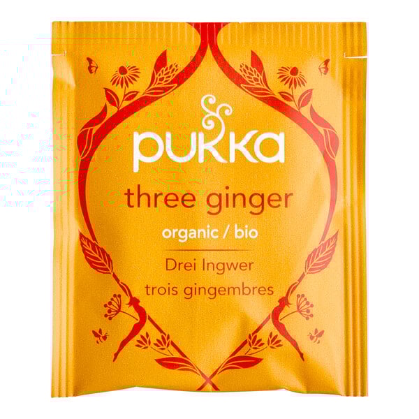 A yellow Pukka Organic Three Ginger tea bag packet with red and white text.