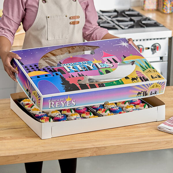 A woman holding a Southern Champion bakery box filled with cupcakes.