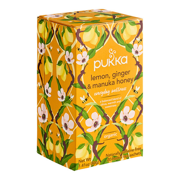A yellow box of Pukka Organic Lemon, Ginger, and Manuka Honey Tea Bags on a table.