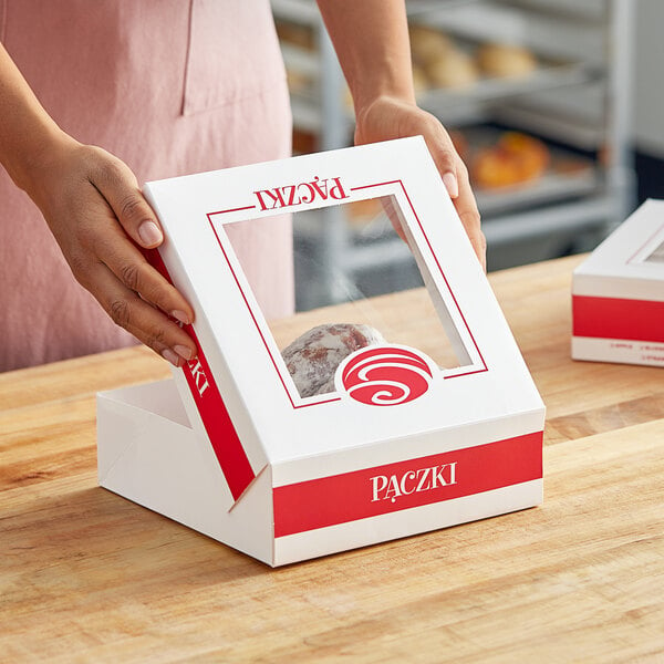 A woman holding a Southern Champion window donut box with a Paczki design.