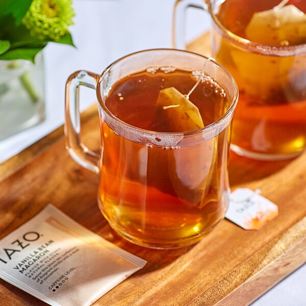 A wooden tray with two mugs of Tazo Vanilla Bean Macaron Tea and a tea bag.