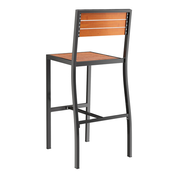 A Lancaster Table & Seating Axel Series black outdoor barstool with a brown faux teak slat seat.