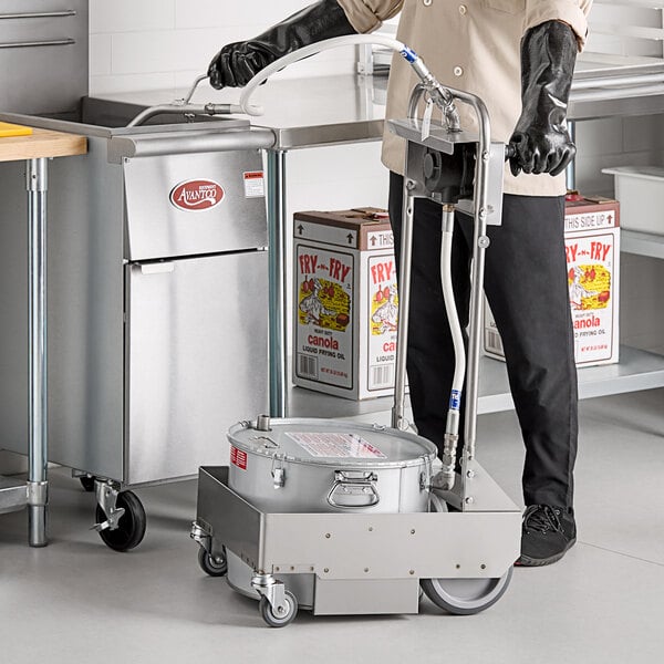 A man in a chef's uniform using a MirOil fryer oil filter machine in a professional kitchen.