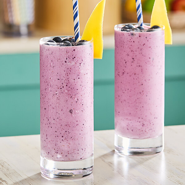 Two glasses of smoothies, one yellow and one pink, with black and yellow straws.