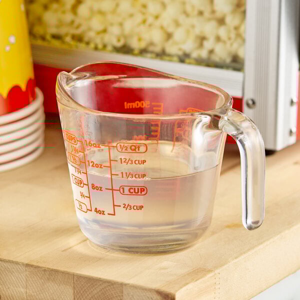 A glass measuring cup with LouAna coconut popping oil in it with a red handle.