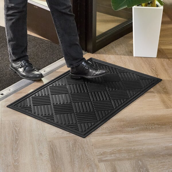 A black 2' x 3' diamond-patterned rubber entrance mat with a beveled edge.