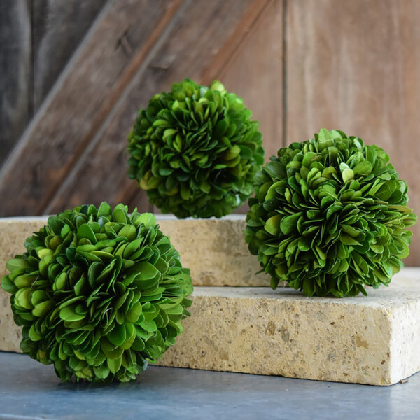 Three Mills Floral Company preserved green boxwood balls on a stone block.