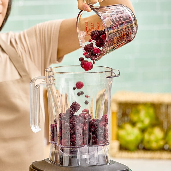 A woman pouring Wyman's Triple Berry Blend into a blender.