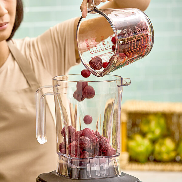 A woman pouring Wyman's frozen cherry blend into a blender.