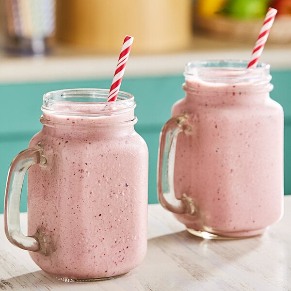 Two glass jars filled with pink Wyman's cherry smoothie with straws.