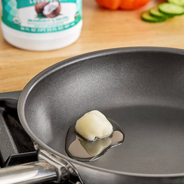 A frying pan with a piece of garlic frying in LouAna Organic Coconut Oil.