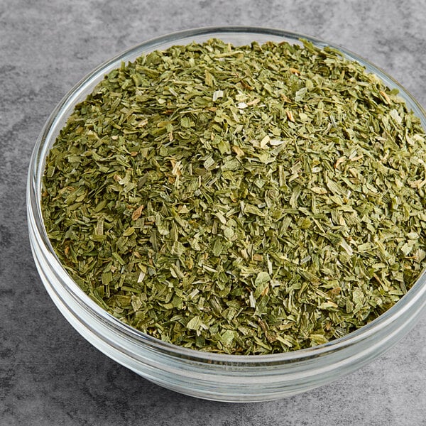 A bowl of Silva Dried Minced Green Onion on a gray surface.