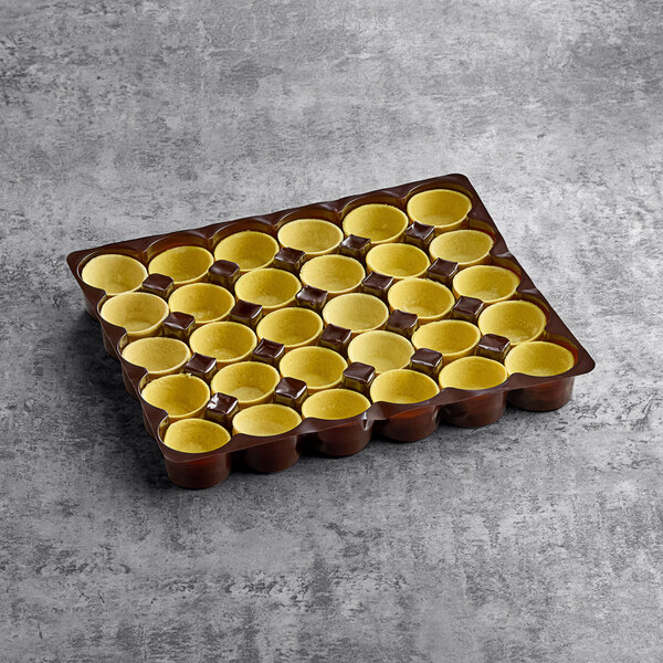 A tray of White Toque gold vegan flared tart shells on a gray surface.