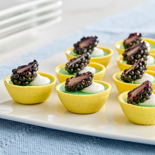 A plate of mini desserts with blackberries in White Toque gold vegan flared tart shells.