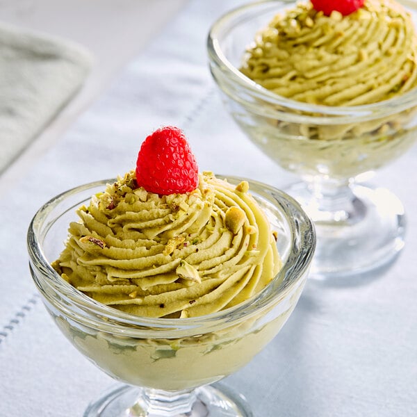 A White Toque pistachio mousse dessert in a glass bowl with a spoon.