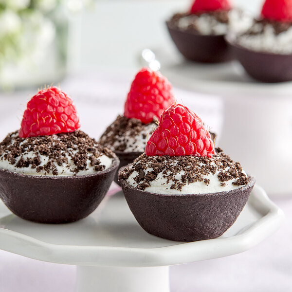 Three White Toque black vegan flared tart shells filled with chocolate and raspberries.
