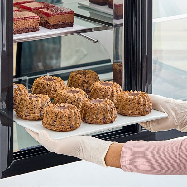 A person holding a tray of White Toque gluten-free vegan molten banana cakes.