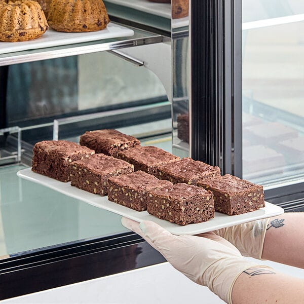 A person holding a plate of White Toque gluten-free vegan brownies.