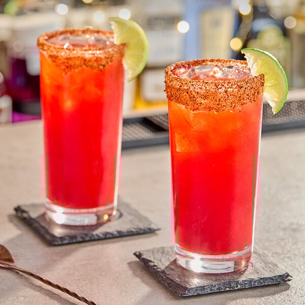 Two glasses of red Chamoy drinks garnished with lime slices.