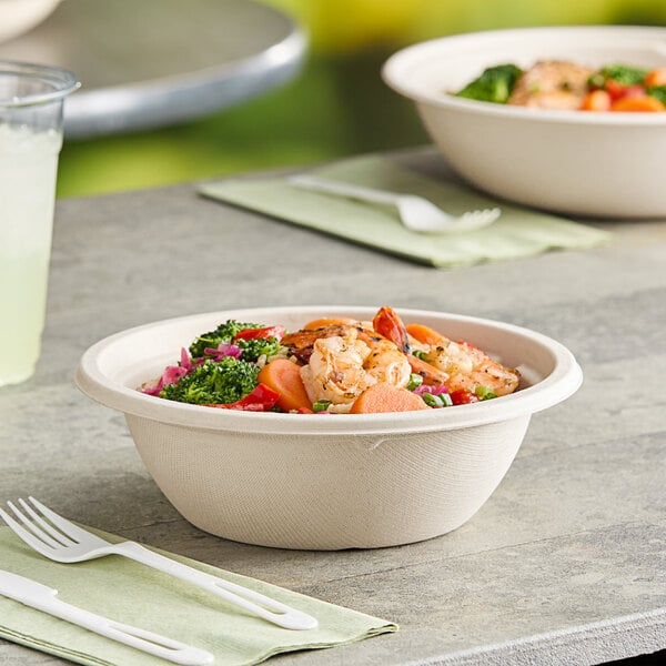 A World Centric compostable take-out bowl filled with food on a table.