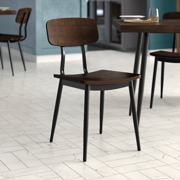 A Lancaster Table & Seating black wooden chair with espresso wood seat and backrest on a table in a restaurant dining area.