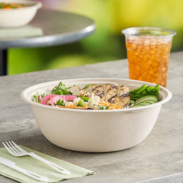 A World Centric compostable fiber bowl filled with food and a drink.