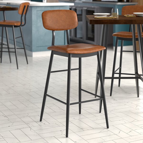 A Lancaster Table & Seating Mid-Century Black Barstool with Cognac Vinyl Padded Seat and Backrest.