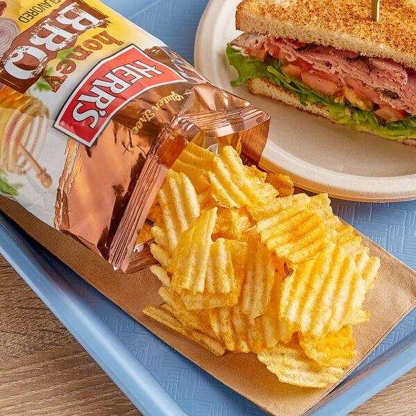 A sandwich on a plate with Herr's Honey BBQ Potato Chips.