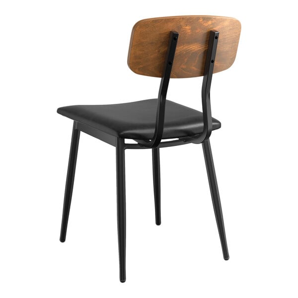 A Lancaster Table & Seating Mid-Century black wood chair with a black vinyl padded seat and vintage wood backrest.