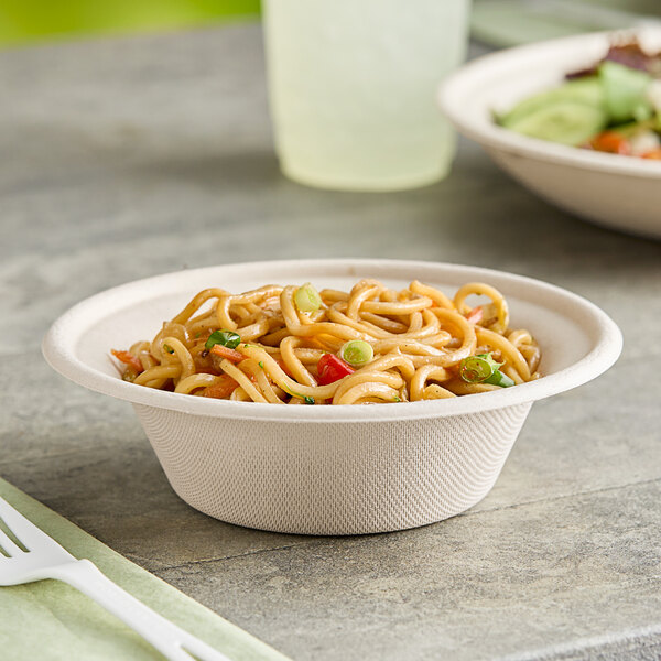 A World Centric compostable fiber bowl filled with noodles and vegetables on a table.