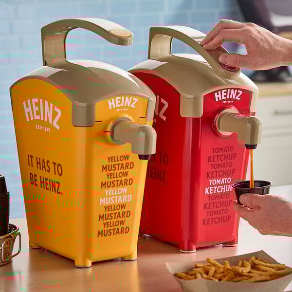 A person using a Heinz ketchup pump to fill a cup of fries.