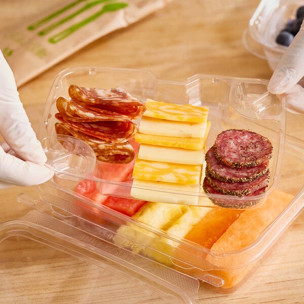 A person holding a Inline Plastics 1-compartment tray insert with food in it.