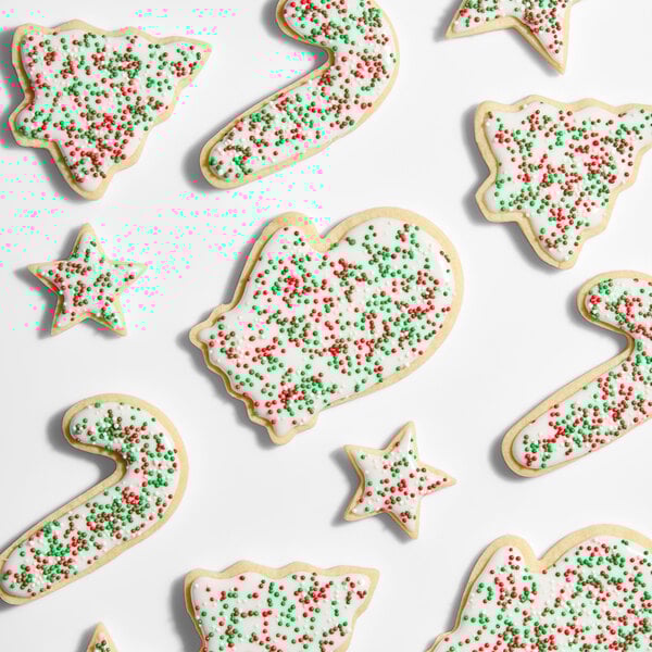 A variety of Christmas-themed sugar cookies decorated with white icing and red and green nonpareil sprinkles.