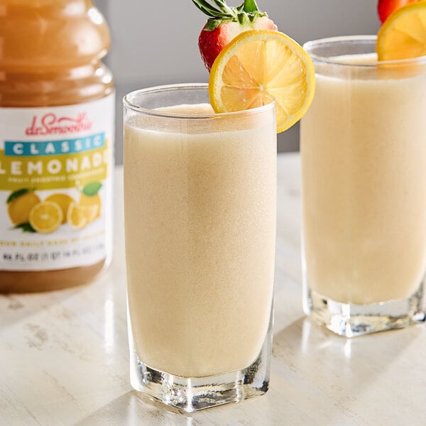 Two glasses of Dr. Smoothie Classic Lemonade with lemon slices and straws.