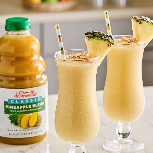 Two glasses of Dr. Smoothie Classic Pineapple Blend next to a bottle of pineapple juice.