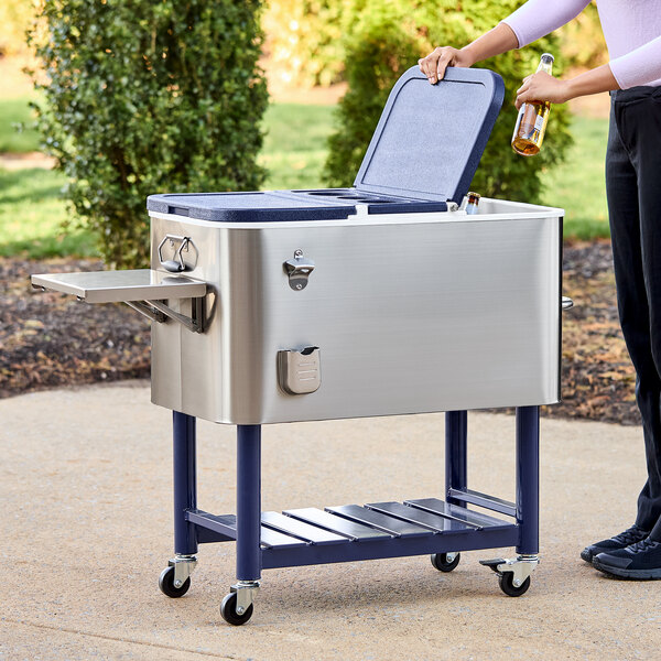 A woman using a Choice stainless steel beverage cooler cart to put a beer bottle in the cooler.