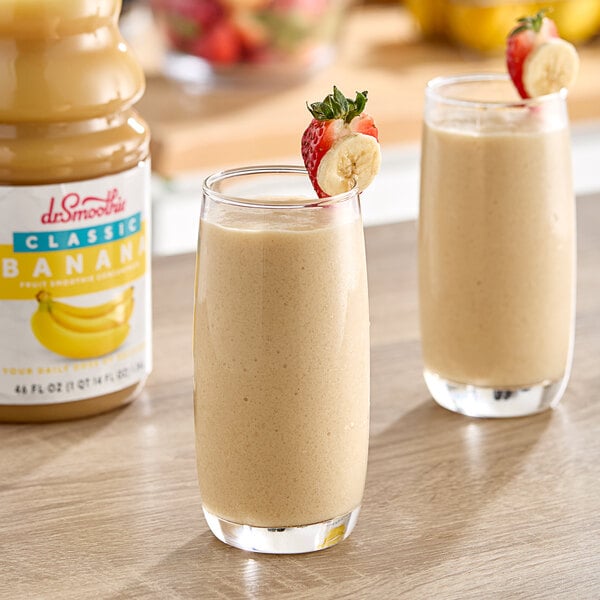 Two glasses of banana smoothie with strawberries on a white background.