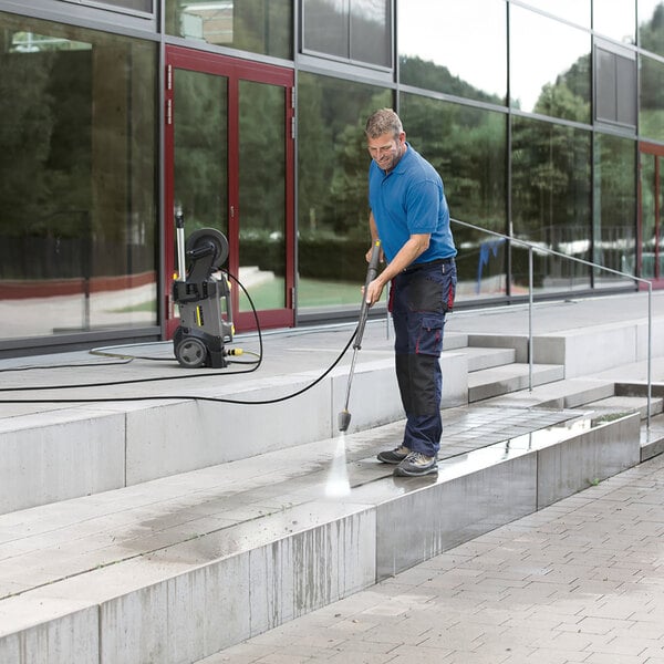 A man cleaning steps with a Karcher electric cold water pressure washer.