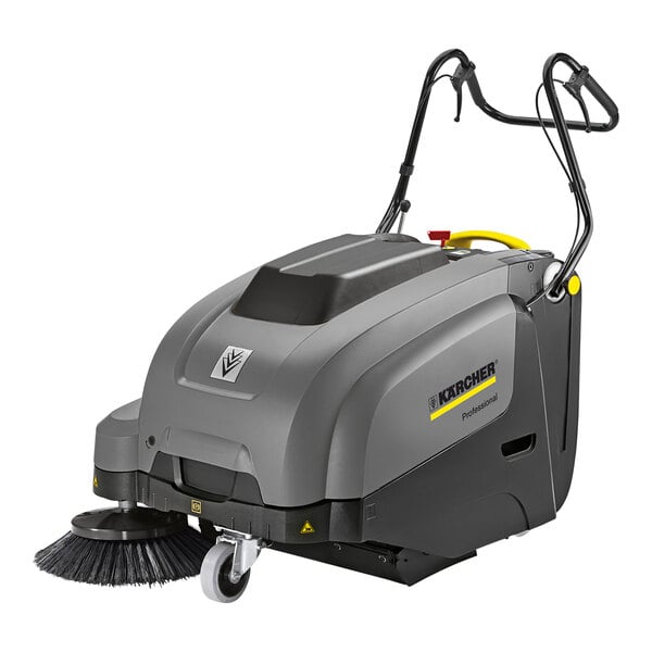 A grey and yellow Karcher walk-behind sweeper with a brush and battery.