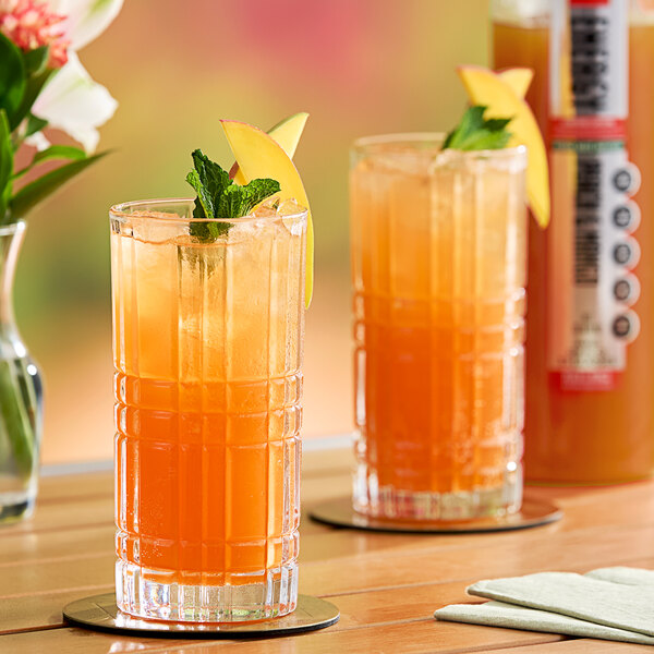A close-up of a glass of orange liquid with fruit.