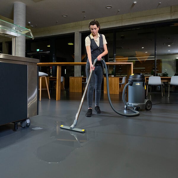 A woman using a Karcher wet / dry vacuum to clean a floor.