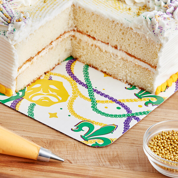 A slice of cake with white frosting and yellow, green, and purple sprinkles on a Southern Champion Mardi Gras cake pad.