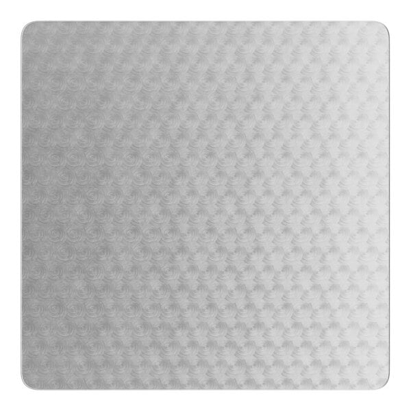 A close-up of a white surface with a silver metal square table top with a pattern on it.