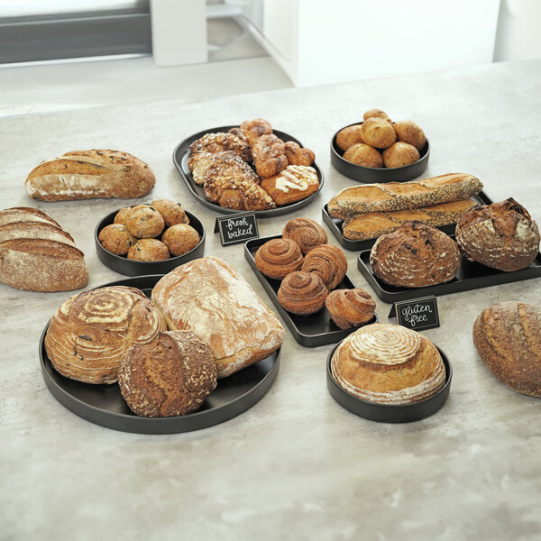 A table with a group of different types of bread on black round Melamine bowls.
