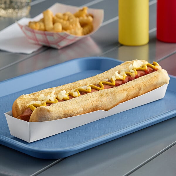 A hot dog with mustard and onions in a white paper footlong hot dog tray.
