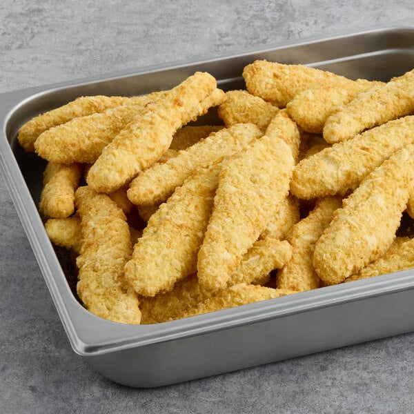 A tray of Brakebush SmartShapes Tater Chip Strip breaded chicken breast strips on a metal tray.